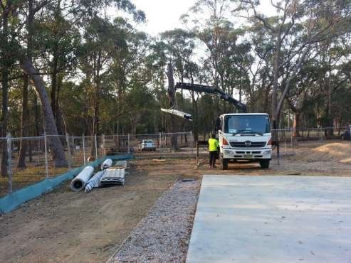Crane truck delivering building materials onto the poured concrete slab for Block B