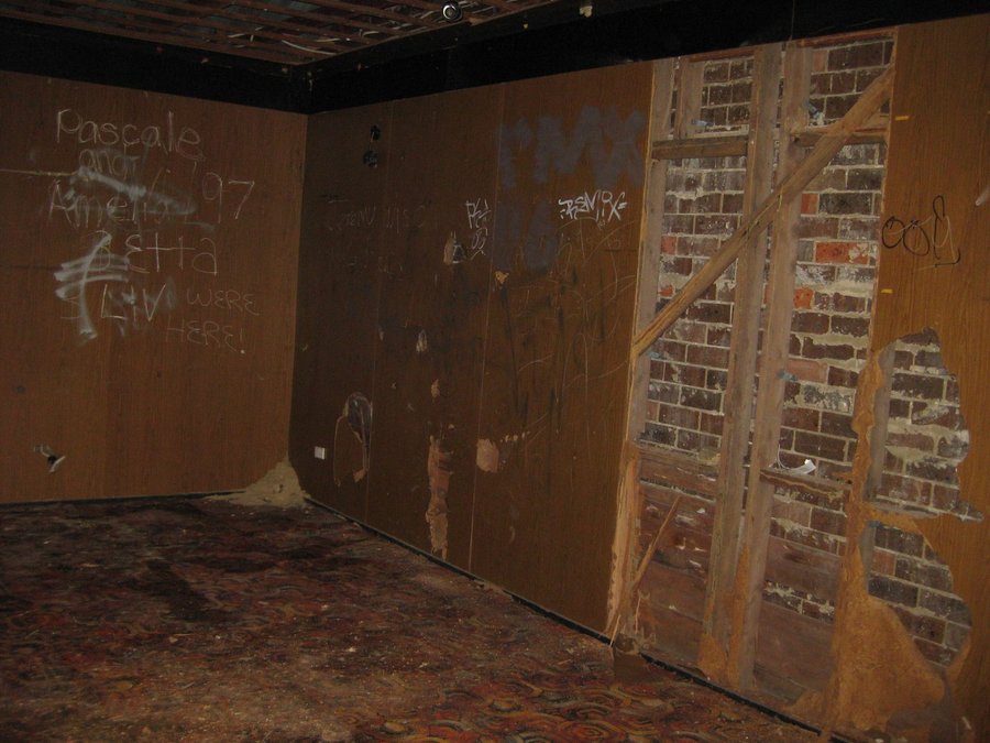 Derelict interior of the Howson Oval sports building before restoration, smashed wall panelling and exposed brick